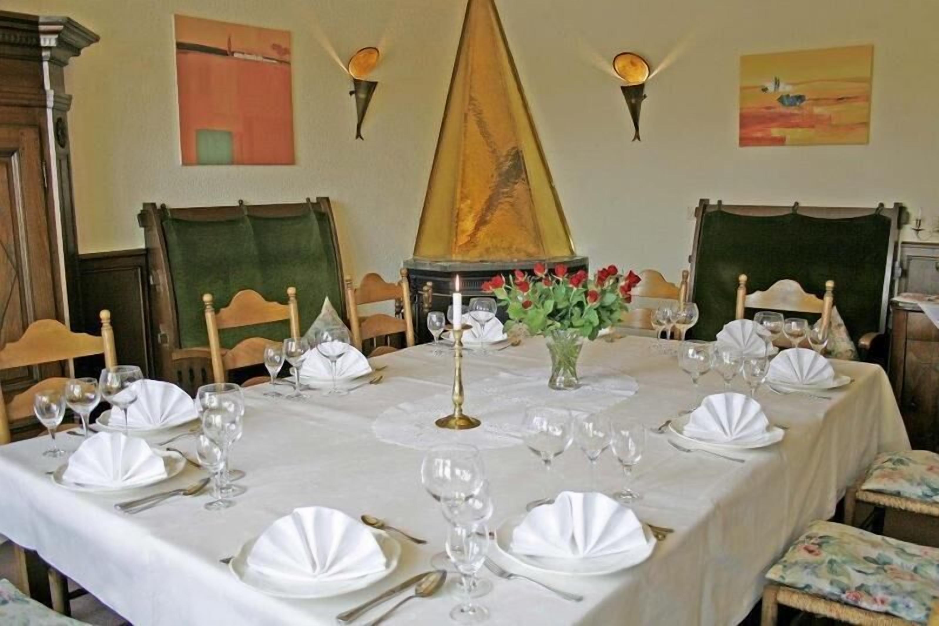 A dining table set for a meal with white tablecloths, plates, and wine glasses.