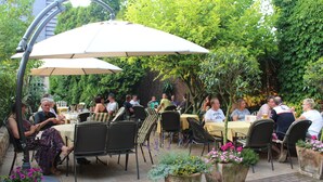An outdoor patio with tables and chairs, surrounded by greenery and a brick wall. - Land-gut-Hotel Lohmann (Drensteinfurt)