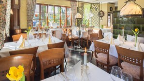 A restaurant with multiple tables set for dining, featuring wooden chairs and white tablecloths. - Land-gut-Hotel Lohmann (Drensteinfurt)