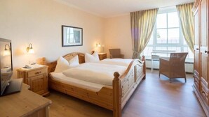 A hotel room with a wooden bed, bedside tables, a desk, and a chair. - Land-gut-Hotel Lohmann (Drensteinfurt)