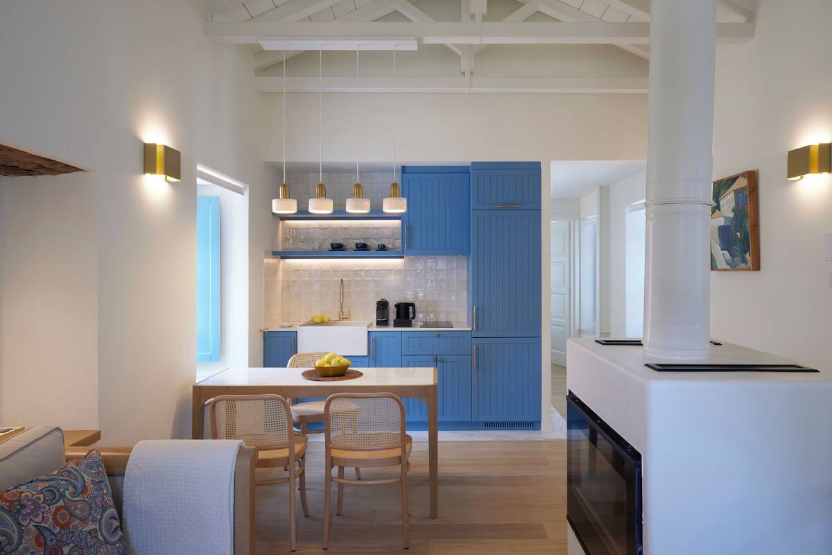 Una cocina moderna con armarios azules, un comedor con sillas de mimbre e iluminación colgante.