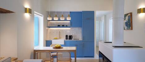 Una cocina moderna con armarios azules, un comedor con sillas de mimbre e iluminación colgante.
