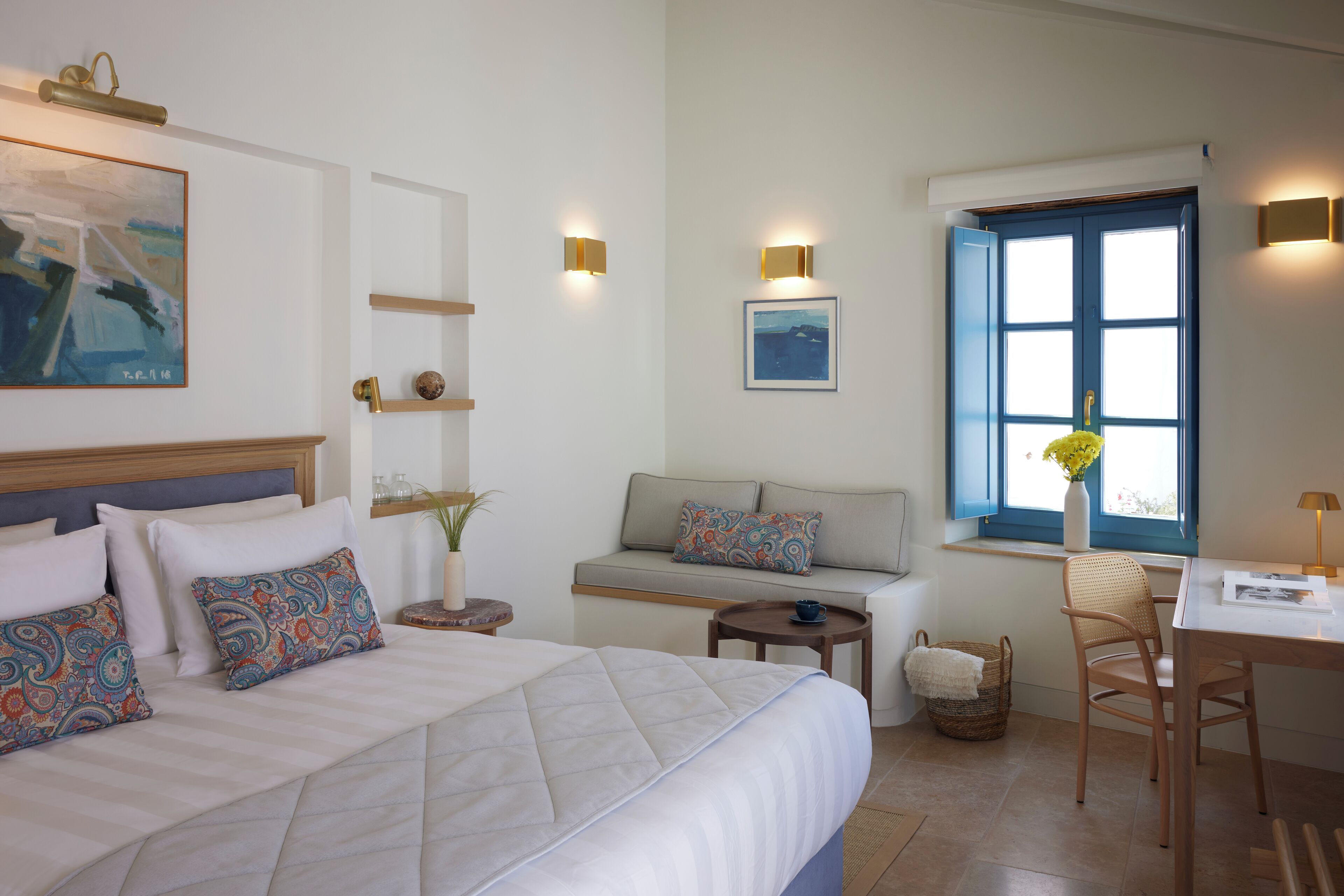 Ein ordentlich eingerichtetes Schlafzimmer mit einem Bett, Nachttischen, einem Sofa, einem Schreibtisch und einem Fenster mit Blick.