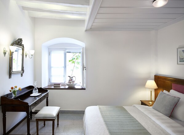 Une chambre à coucher comprenant un lit, une table de chevet, une lampe et une fenêtre donnant sur un paysage verdoyant.