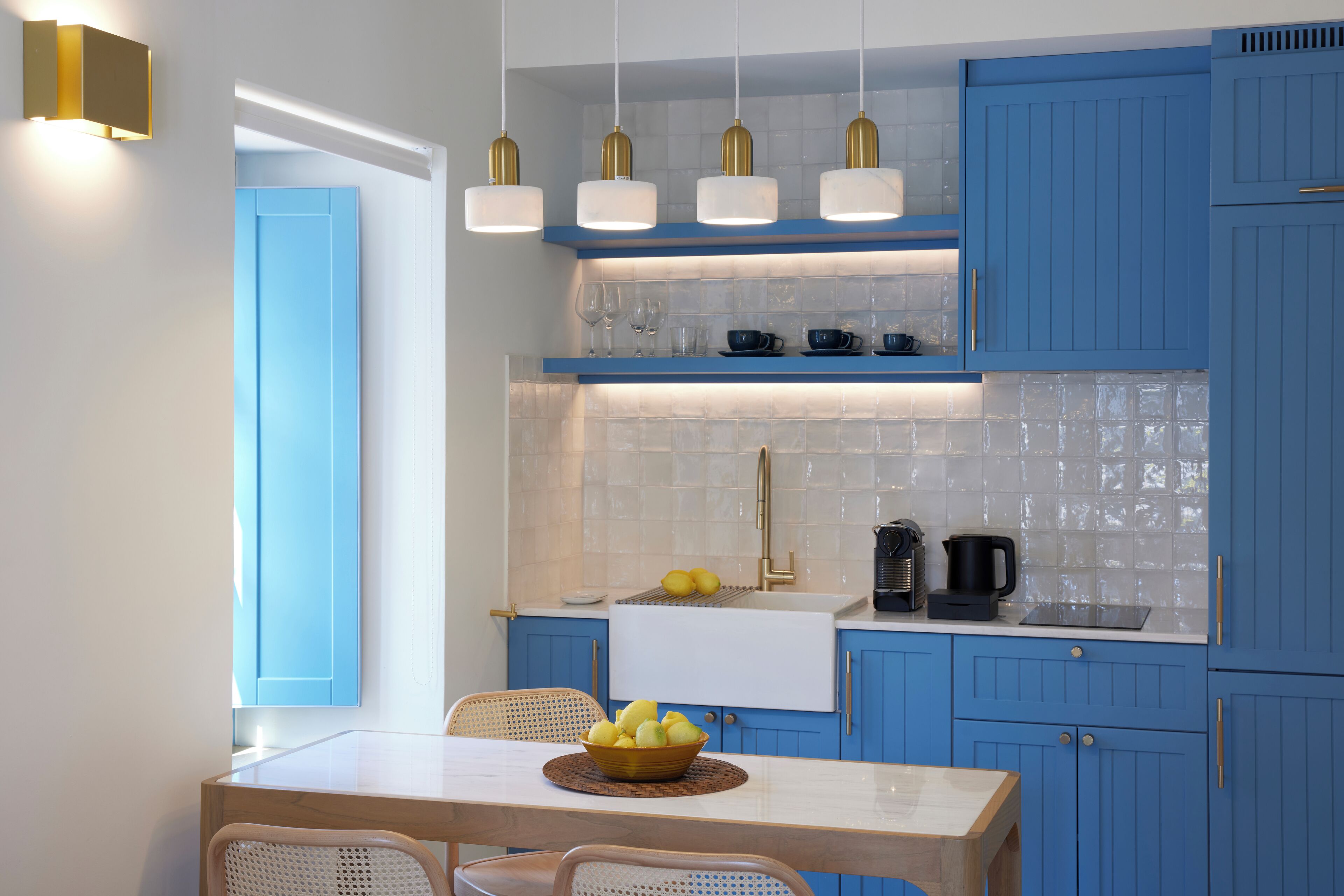 A modern kitchen with blue cabinets, a white countertop, and a dining area with a table and chairs.