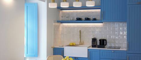 A modern kitchen with blue cabinets, a white countertop, and a dining area with a table and chairs.