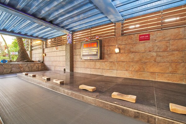 A stone wall with a sign, wooden benches, and a metal roof.