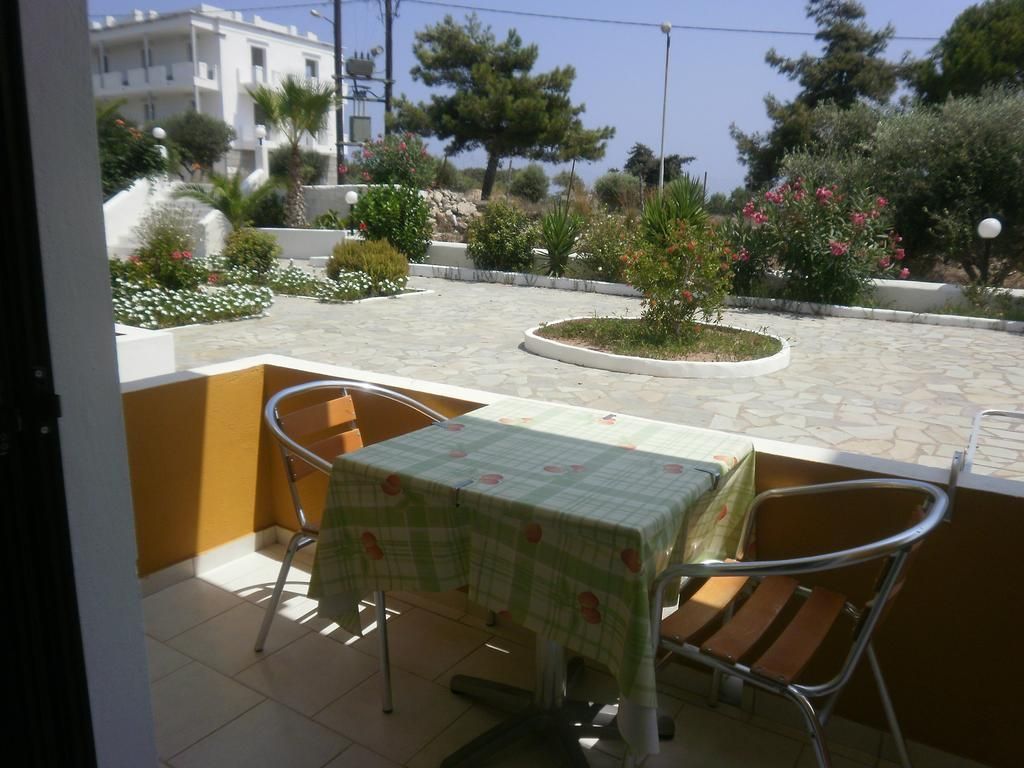 Una terrazza esterna con tavolo e sedie, circondata da un giardino ricco di piante e fiori.