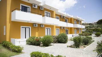 A multi-story residential building with balconies, air conditioning units, and a landscaped garden area.