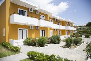 A multi-story residential building with balconies, air conditioning units, and a landscaped garden area.