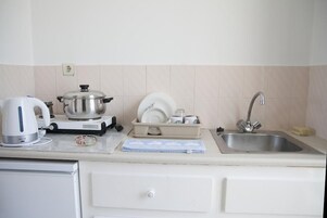 Una cocina con tetera, olla, escurreplatos y pileta.