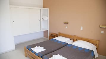Quarto com duas camas de solteiro, um guarda-roupa e uma pequena mesa de cabeceira.