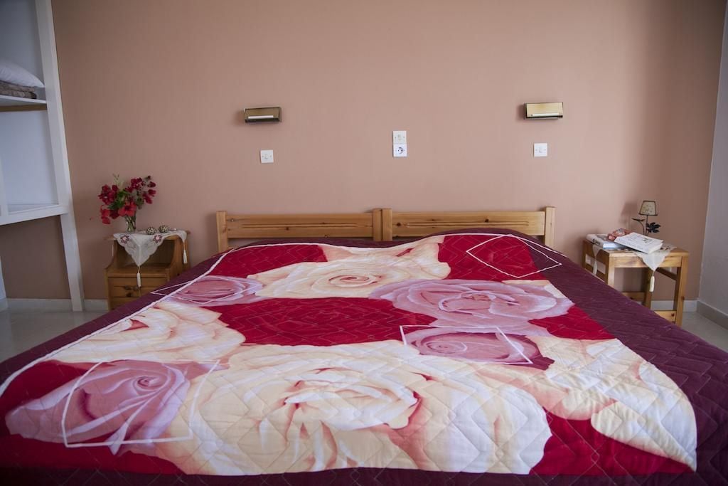 A bedroom with a large bed, two bedside tables, a nightstand, and a wall-mounted light fixture.