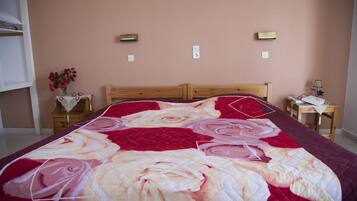 A bedroom with a large bed, two bedside tables, a nightstand, and a wall-mounted light fixture.