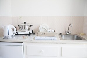 A kitchen with a kettle, a pot, a sink, and a dish rack. - Manolis Studios (Kos)