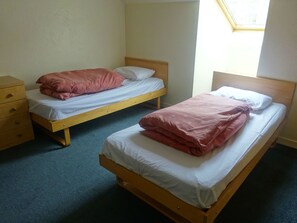 Two single beds with wooden frames and white bedding, a wooden dresser with drawers, and a skylight above the beds. - Edinburgh Metro Youth Hostel (Edinburgh)