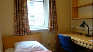 A room with a bed, a desk with a lamp, and a window with patterned curtains. - Edinburgh Metro Youth Hostel (Edinburgh)