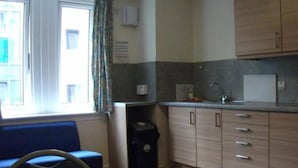 A compact kitchen with a sink, cabinets, and a window with curtains. - Edinburgh Metro Youth Hostel (Edinburgh)
