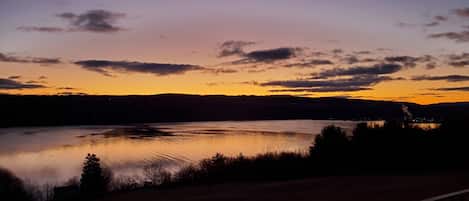 A lake at dusk with a clear sky and distant hills.