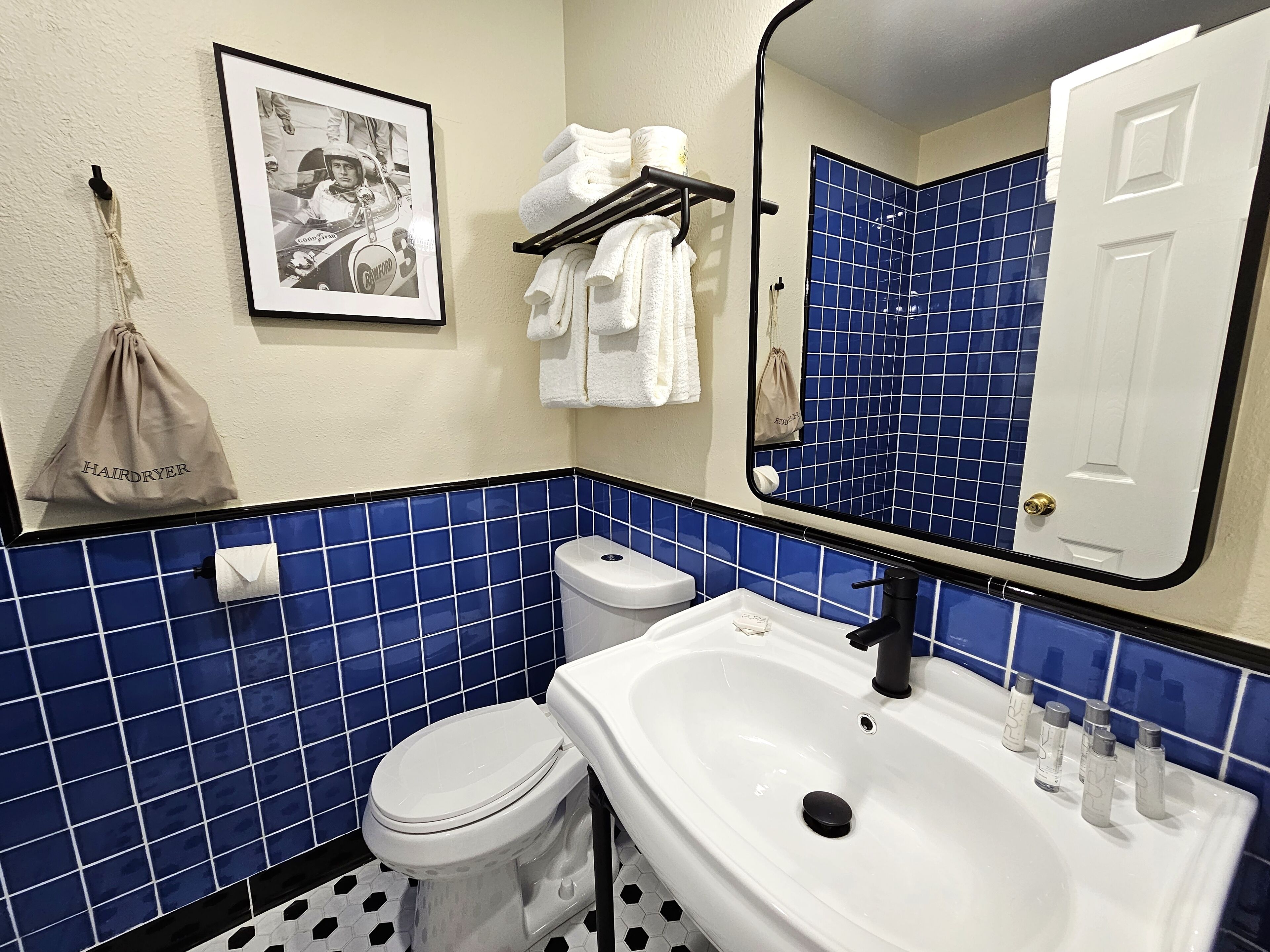 A bathroom with a toilet, sink, and blue-tiled walls.