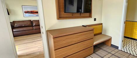 Een kamer met een houten dressoir, een bankje, een spiegel en een deur naar een andere ruimte.