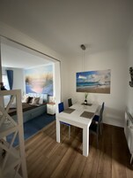 Una habitación con una mesa de comedor, sillas, una cama con vistas a la playa y un cuadro del océano.