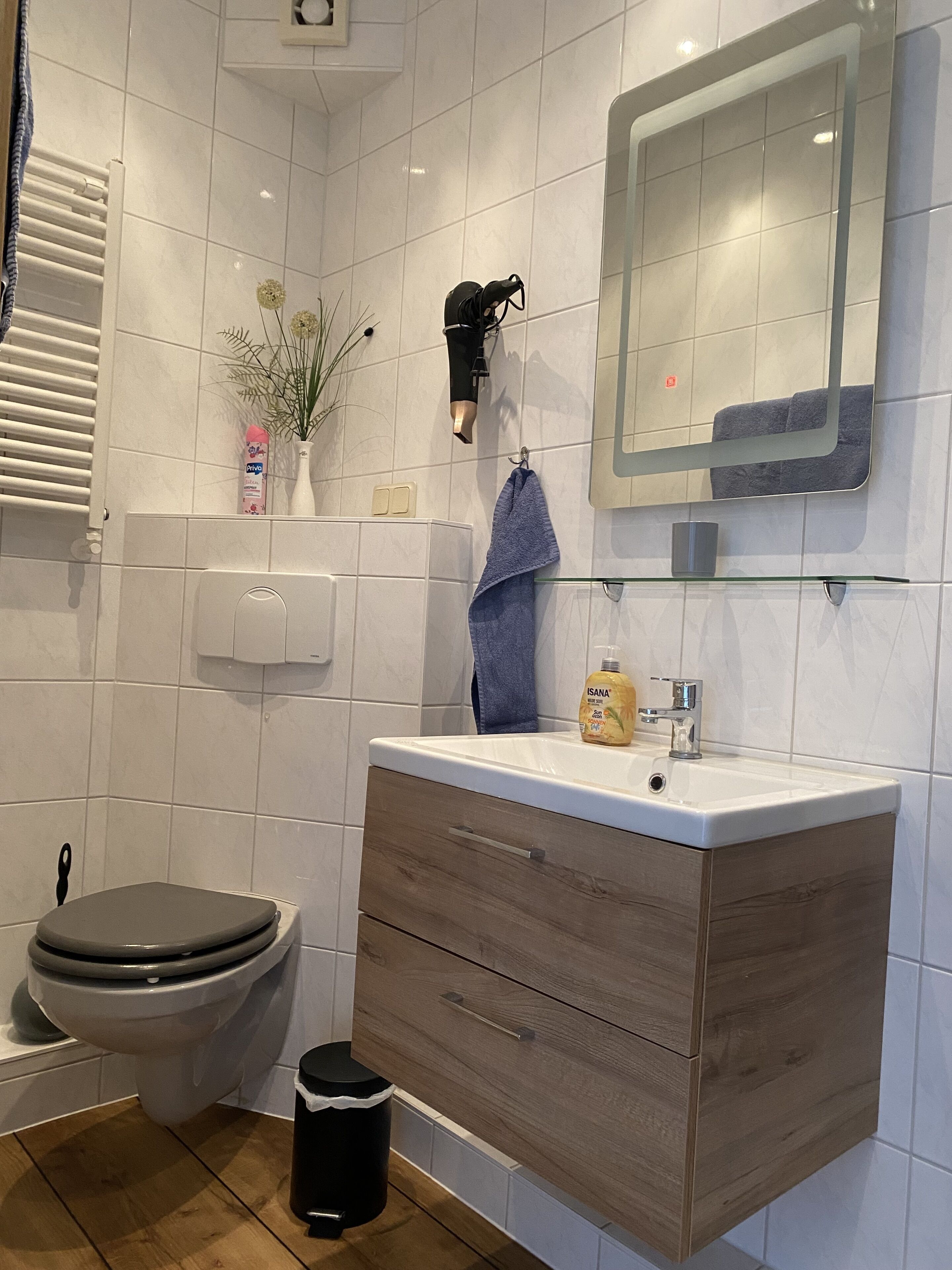 A modern bathroom with a toilet, vanity with a mirror, and a sink.