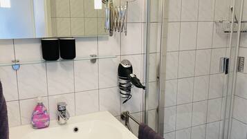 Un bagno moderno con un lavandino bianco, uno specchio e una cabina doccia in vetro.