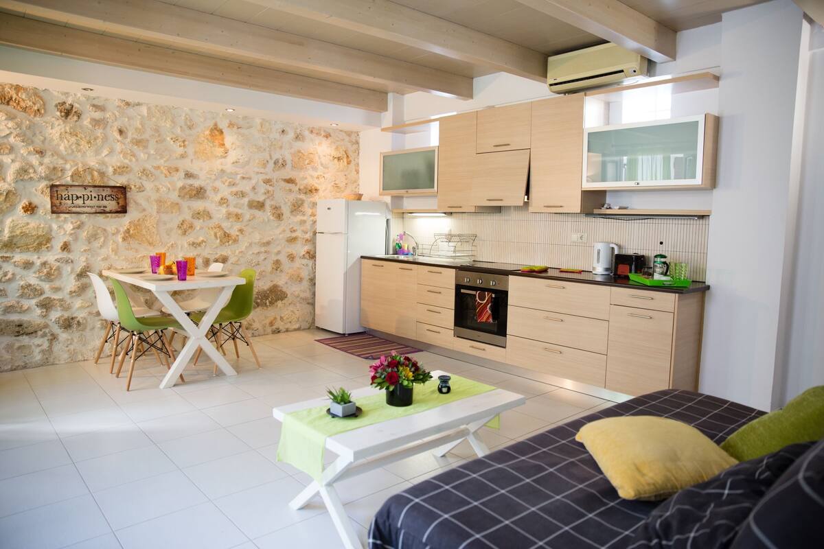 Un espacio habitable pequeño con una pared de piedra, kitchenette, comedor y sofá.