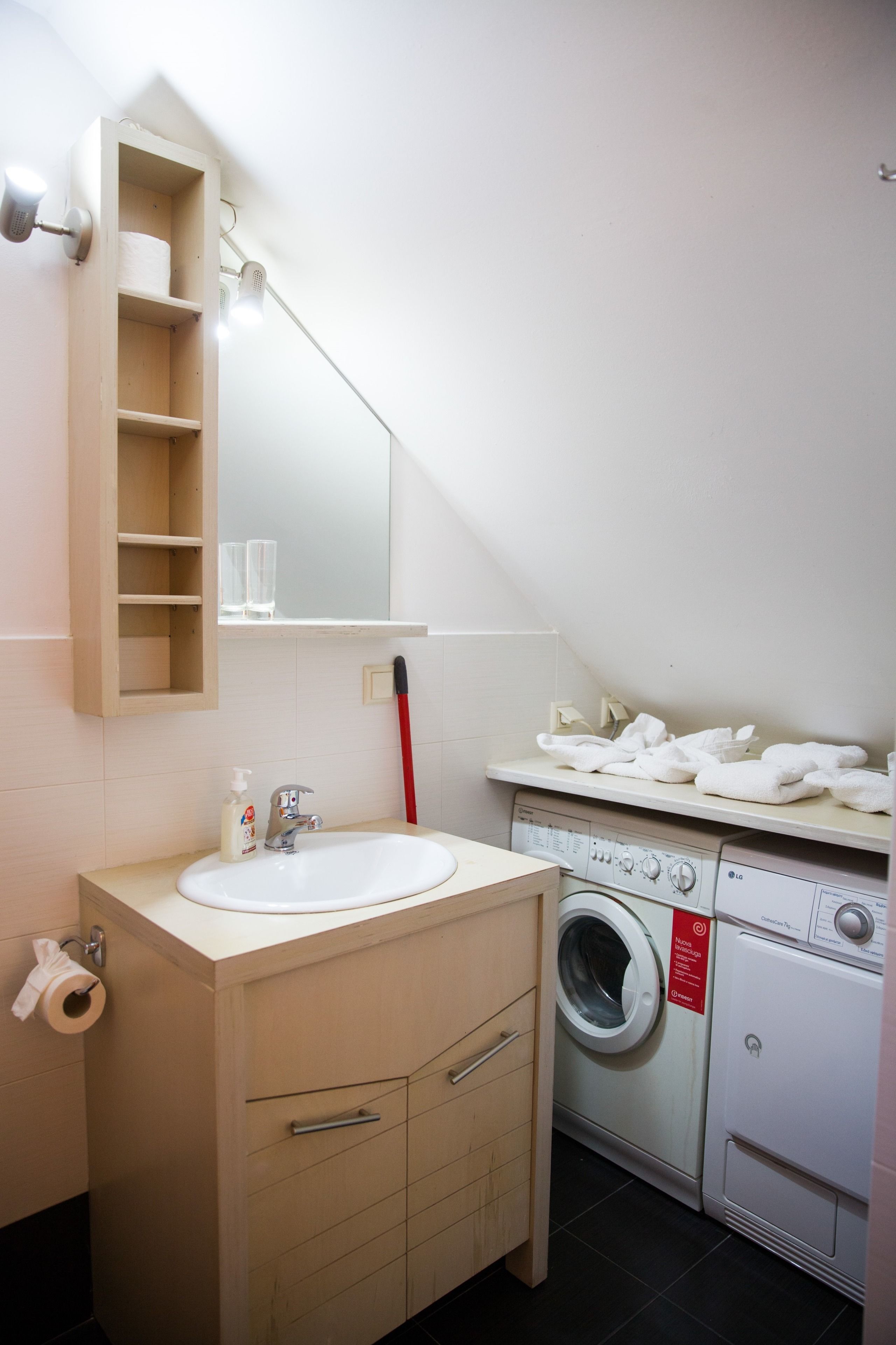 Un bany amb un lavabo, mirall, barra de tovalloles i una rentadora.