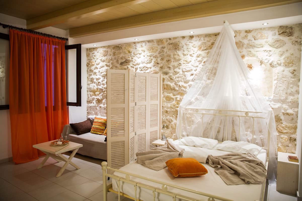 Un dormitorio con cama, una mesita, un sofá y un muro de piedra.