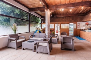 A lounge area with wicker furniture, a children's play area, and a vending machine. - Hotel Slovan (Vysoké Tatry)
