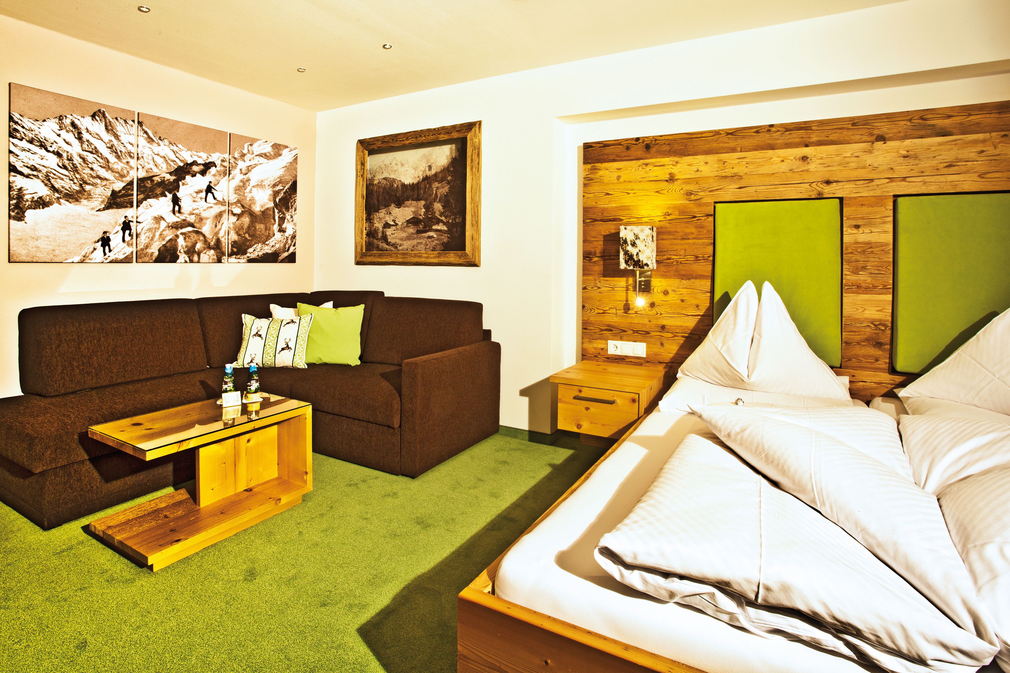 Ein Hotelzimmer mit einem Bett, einem Nachttisch aus Holz, einem Couchtisch aus Holz, einem braunen Sofa und grünen Wänden.