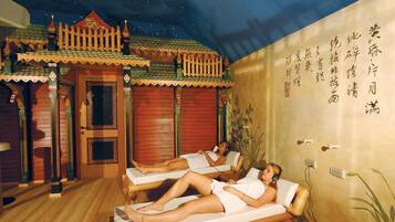 Experience a serene spa setting with traditional Asian architecture and decorative elements, featuring two massage tables and a culturally themed ambiance.