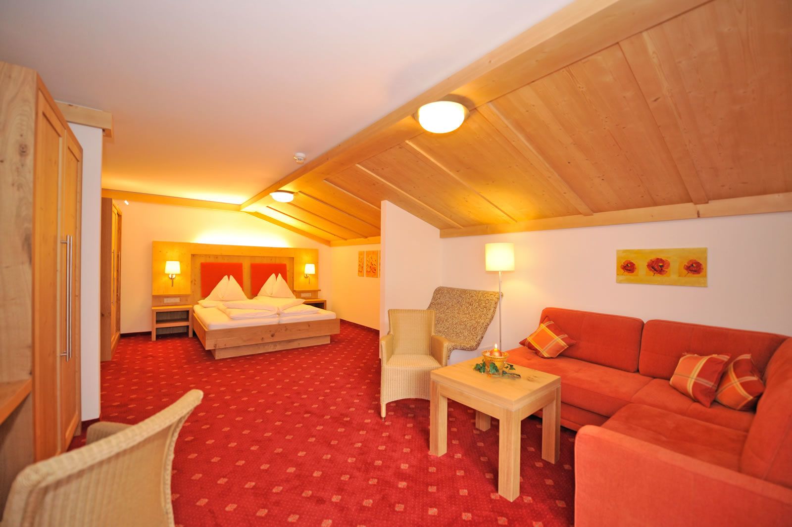A hotel room with a bed, a sofa, a chair, and a small table.