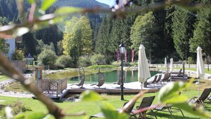 A lakeside resort with a wooden deck, lounge chairs, and a small pavilion. - Landhotel Alpenhof (Filzmoos)