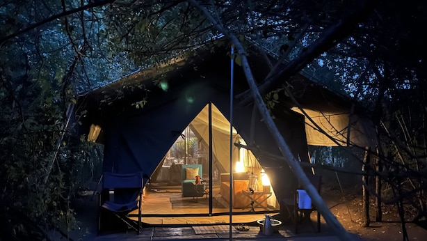 A tent with a glass door, a small table, and a chair inside.
