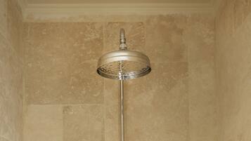 A shower with a high ceiling and a wall-mounted soap dispenser.