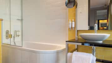 Un baño moderno con ducha envuelta en vidrio, una bañera blanca, un lavabo con espejo y piso de baldosas.