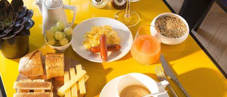 Una mesa de desayuno con diversos alimentos, como tostadas, queso, salchichas, huevos y una taza de café.