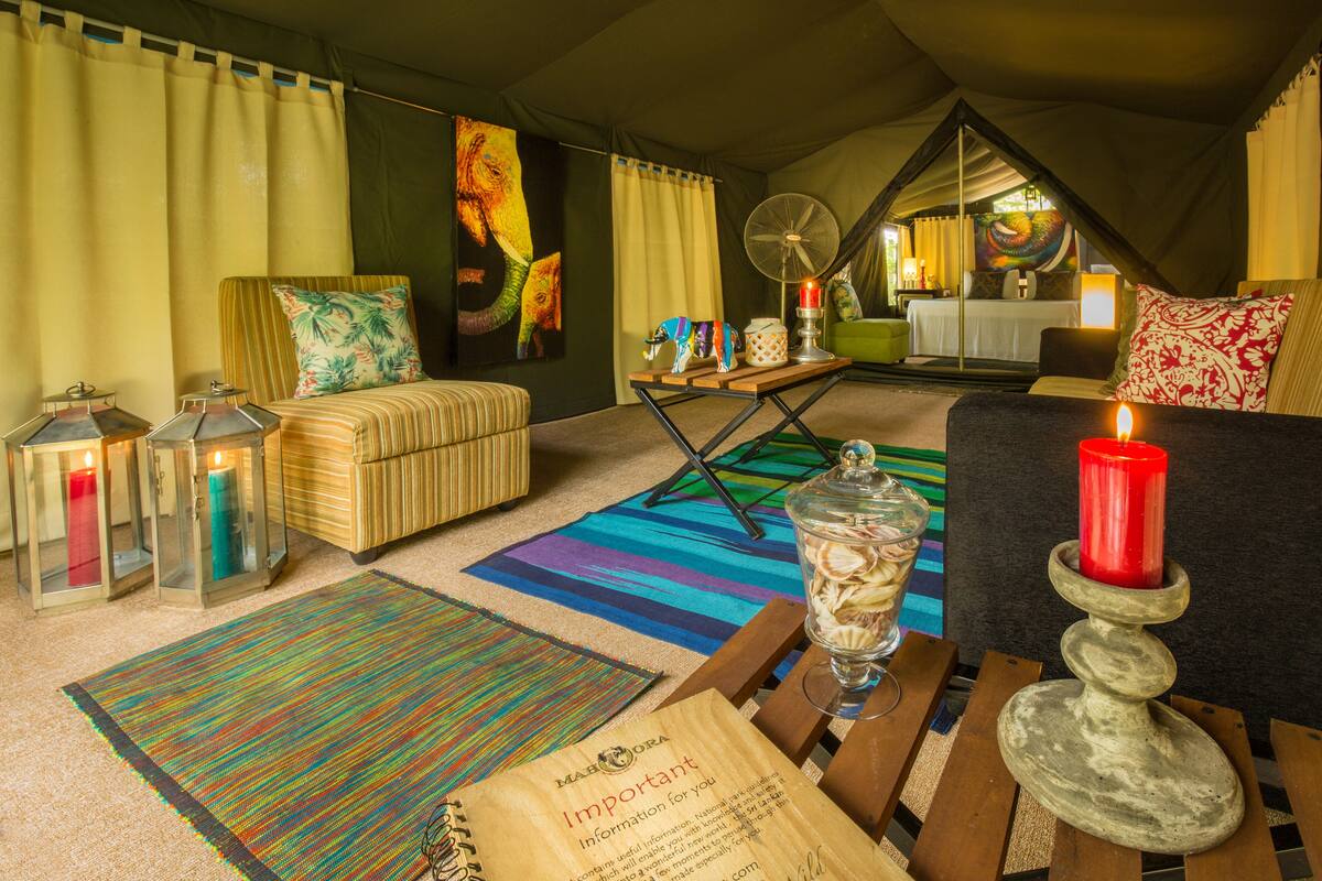A cozy tented room with a bed, a table with candles, and a colorful rug.