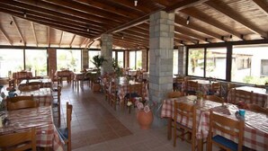 Un restaurant amb bigues de fusta, taules amb mantells quadriculats i grans finestres.