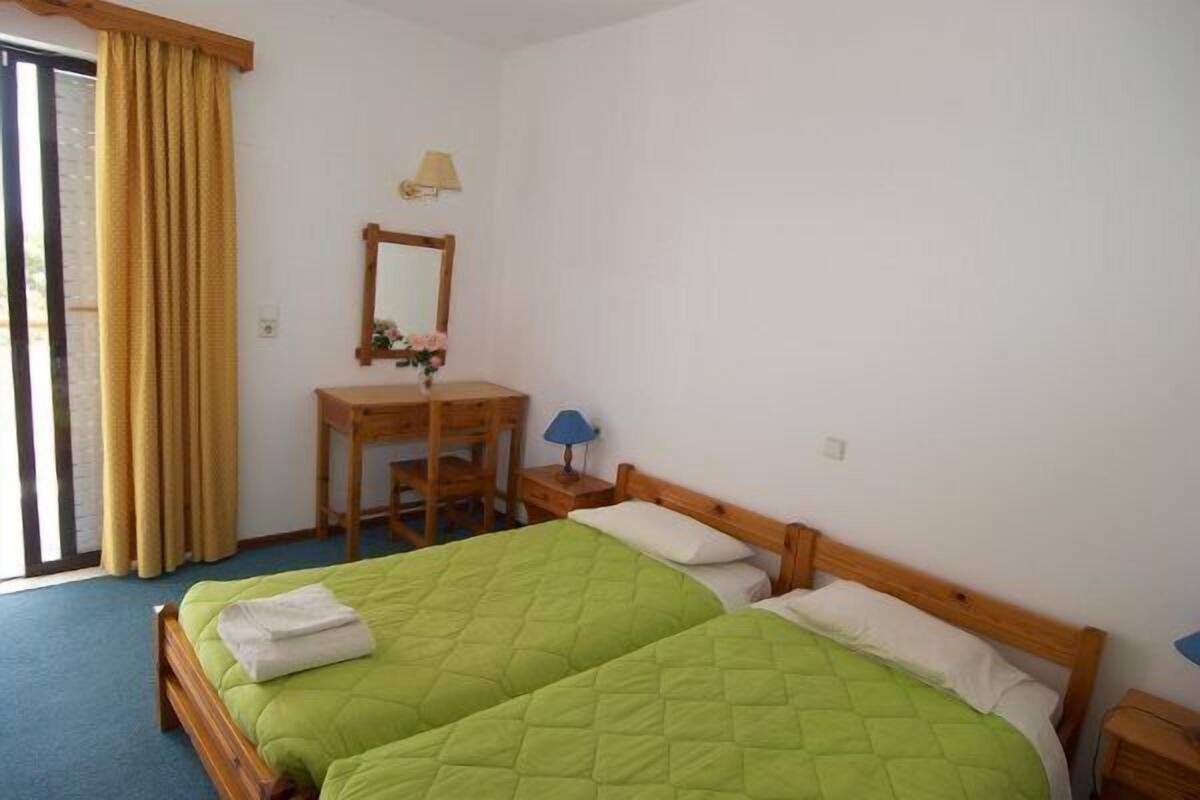 A room with two beds, a desk, a chair, a lamp, and a mirror.