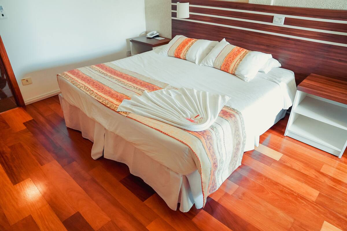 A neatly made bed with a striped bedspread and a folded white towel.