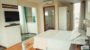 A hotel room with a bed, a TV, a wardrobe, and a bathroom visible through a glass door. - Hotel Imperial (Quatro Barras)