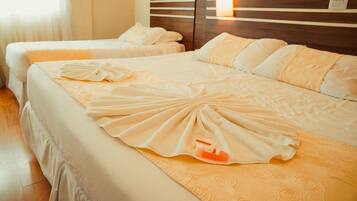 Une chambre d’hôtel avec deux lits, chacun agrémenté d’une serviette soigneusement pliée et d’un flacon de lotion.