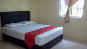 Una cama individual con cabecera oscura, ropa de cama blanca y una manta roja.