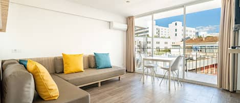 Un soggiorno moderno con un divano componibile, un tavolo da pranzo e un'ampia finestra con vista sugli edifici.