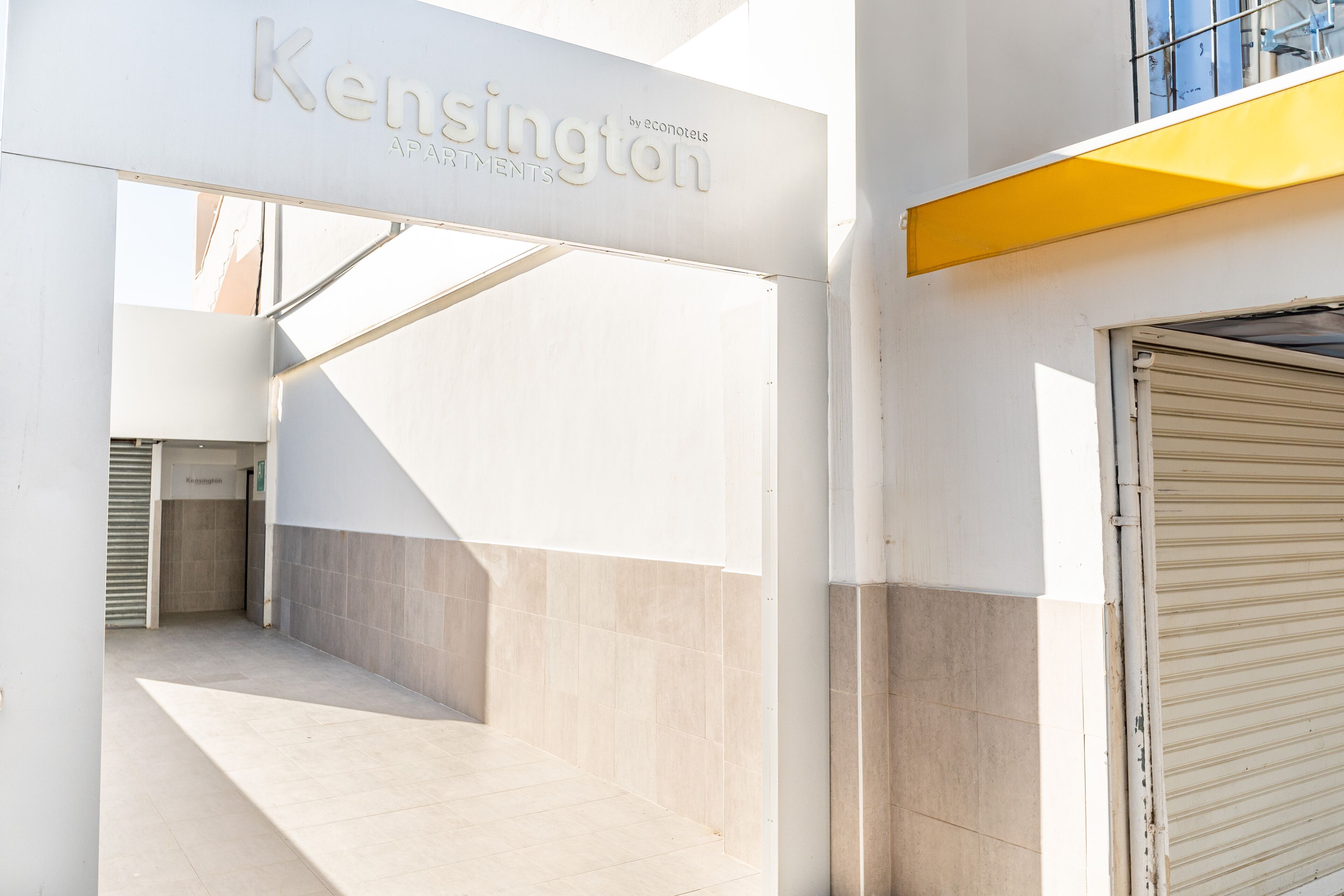 Una entrada moderna de edificio con un letrero que dice "Kensington by econotels APARTMENTS".