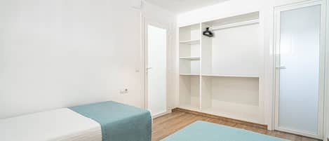 Een kamer met twee bedden, een kledingkast en een spiegel.